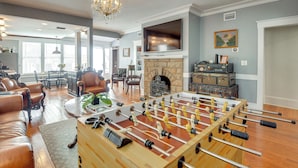 A living room with a foosball table, leather furniture, a fireplace, and a television. - Historic Home < 2 Mi to Daytona Beach & Pier! (Daytona Beach)