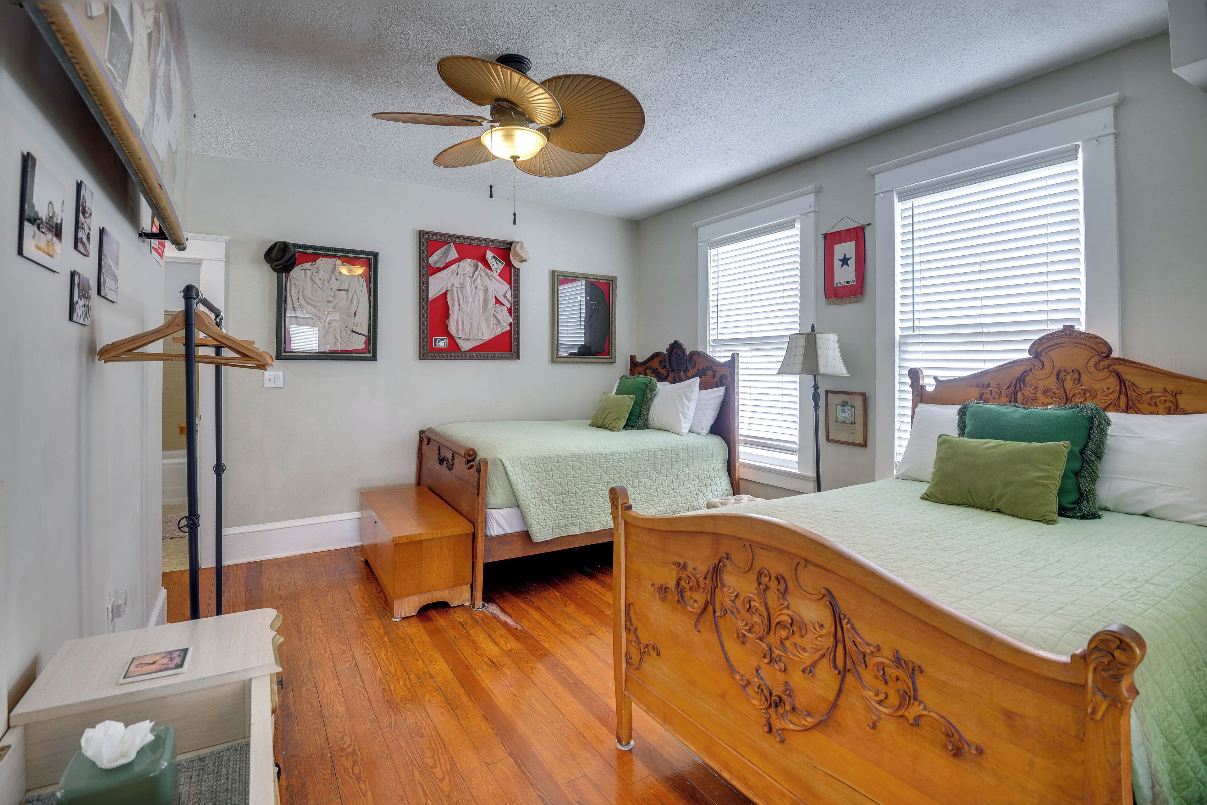A bedroom with two beds, a ceiling fan, and a wooden floor.