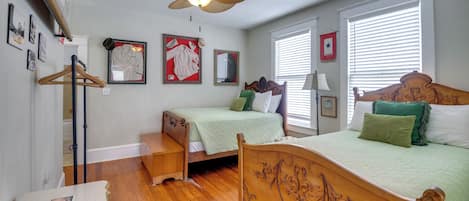 A bedroom with two beds, a ceiling fan, and a wooden floor.