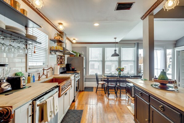 A kitchen with a wooden floor, a dining area with a table and chairs, and a window with blinds.