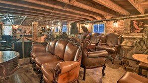 A rustic interior with exposed wooden beams, leather armchairs, and a brick wall. - Historic Home < 2 Mi to Daytona Beach & Pier! (Daytona Beach)