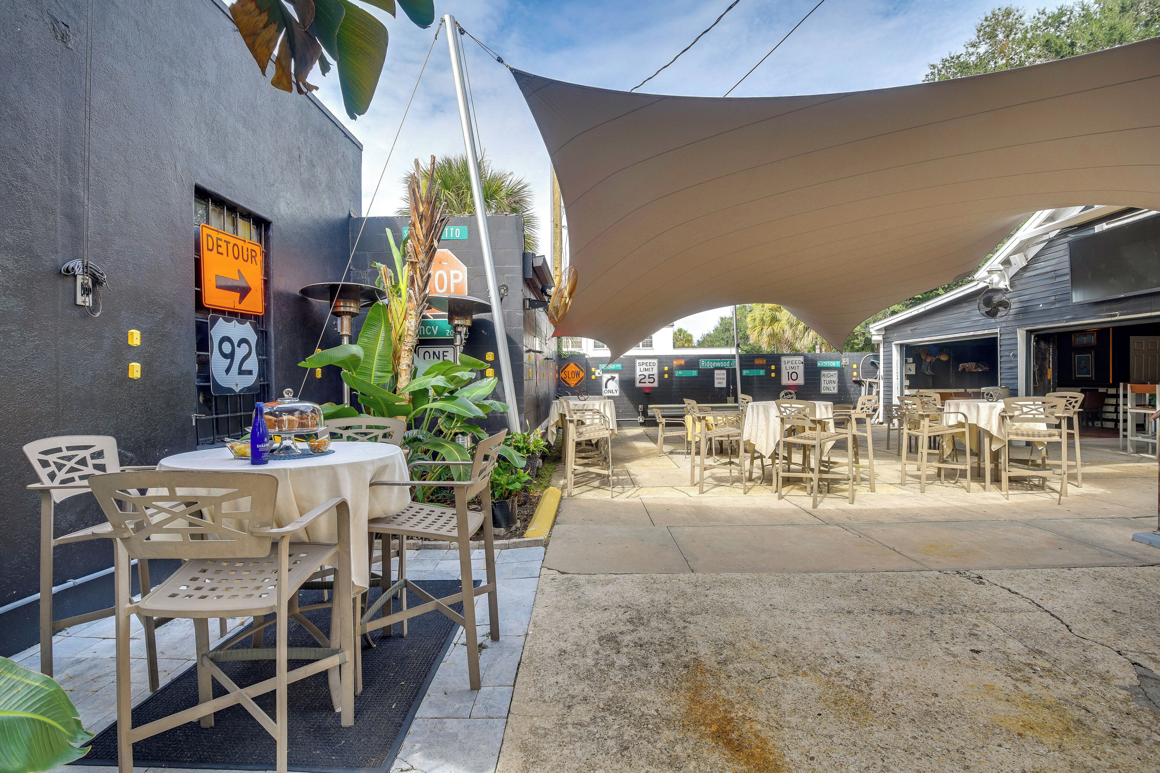 An outdoor seating area with tables and chairs, a speed limit sign, and a detour sign.