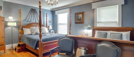 Une chambre à coucher avec un lit à baldaquin, deux fauteuils, un bureau et un lustre.