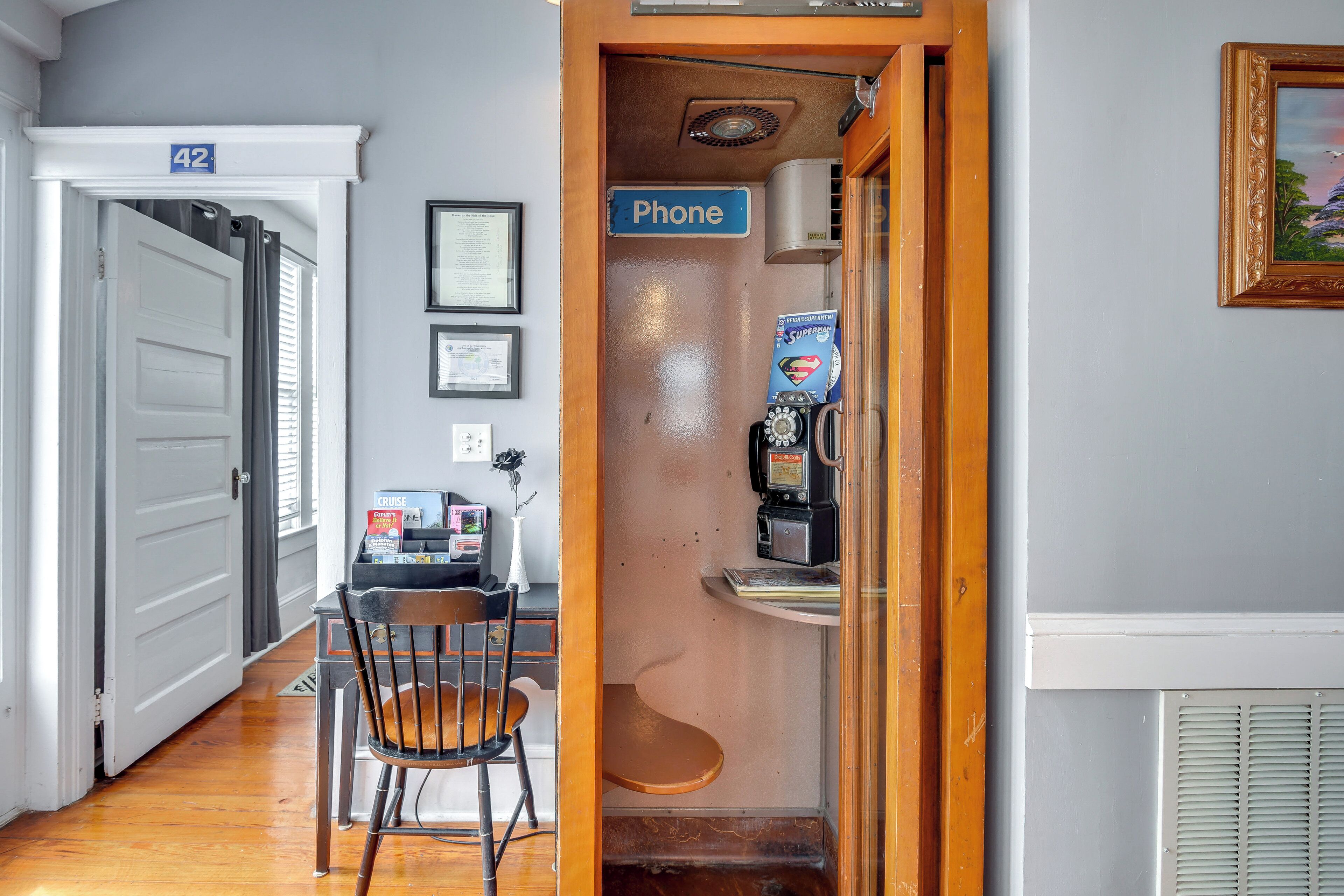 A hallway with a door marked '42', a phone station, and a chair.