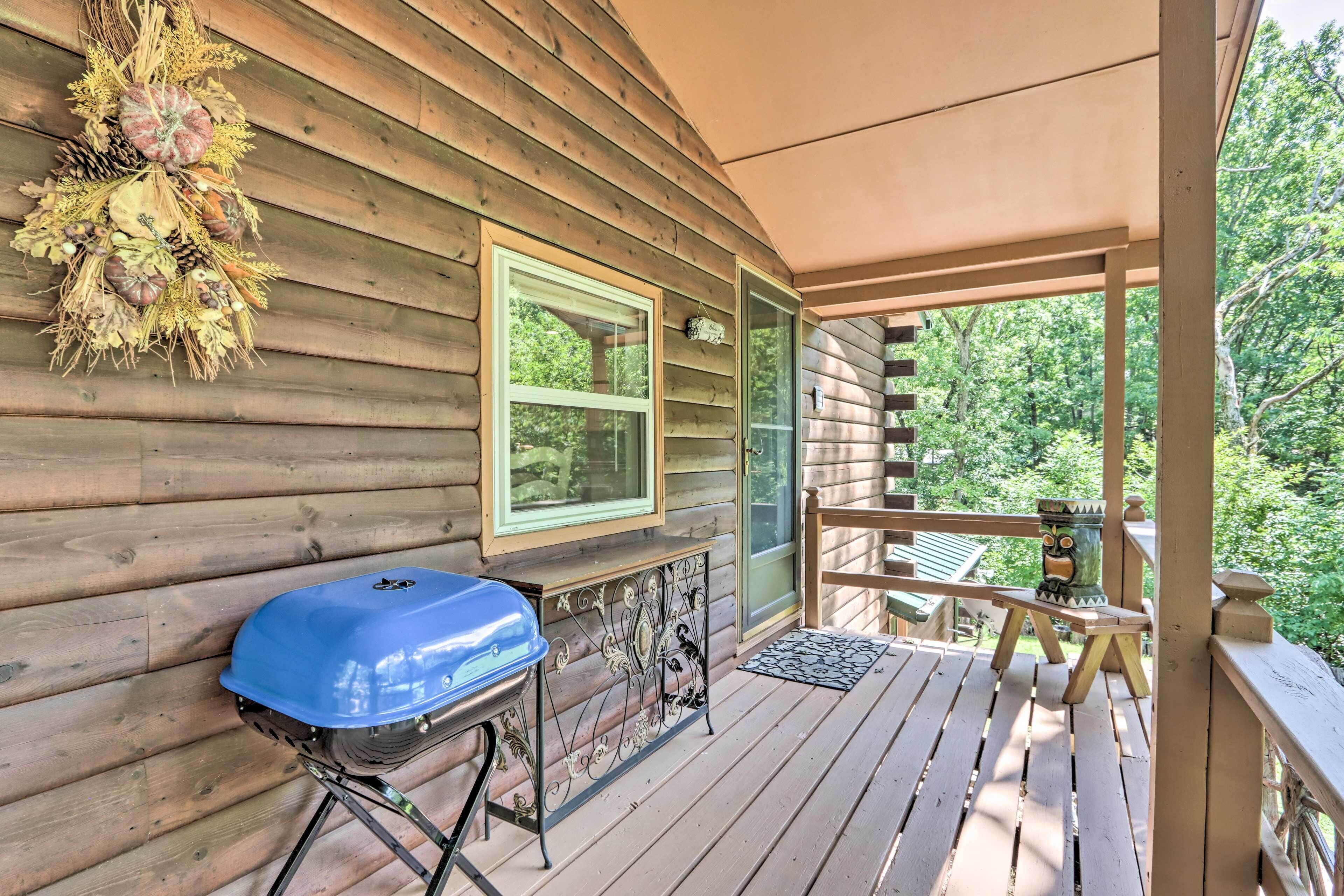 A wooden cabin with a covered porch, a barbecue grill, and a decorative wreath.