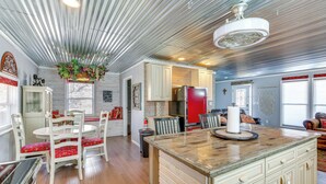 A spacious kitchen with a central island, wooden cabinets, and a hanging plant.