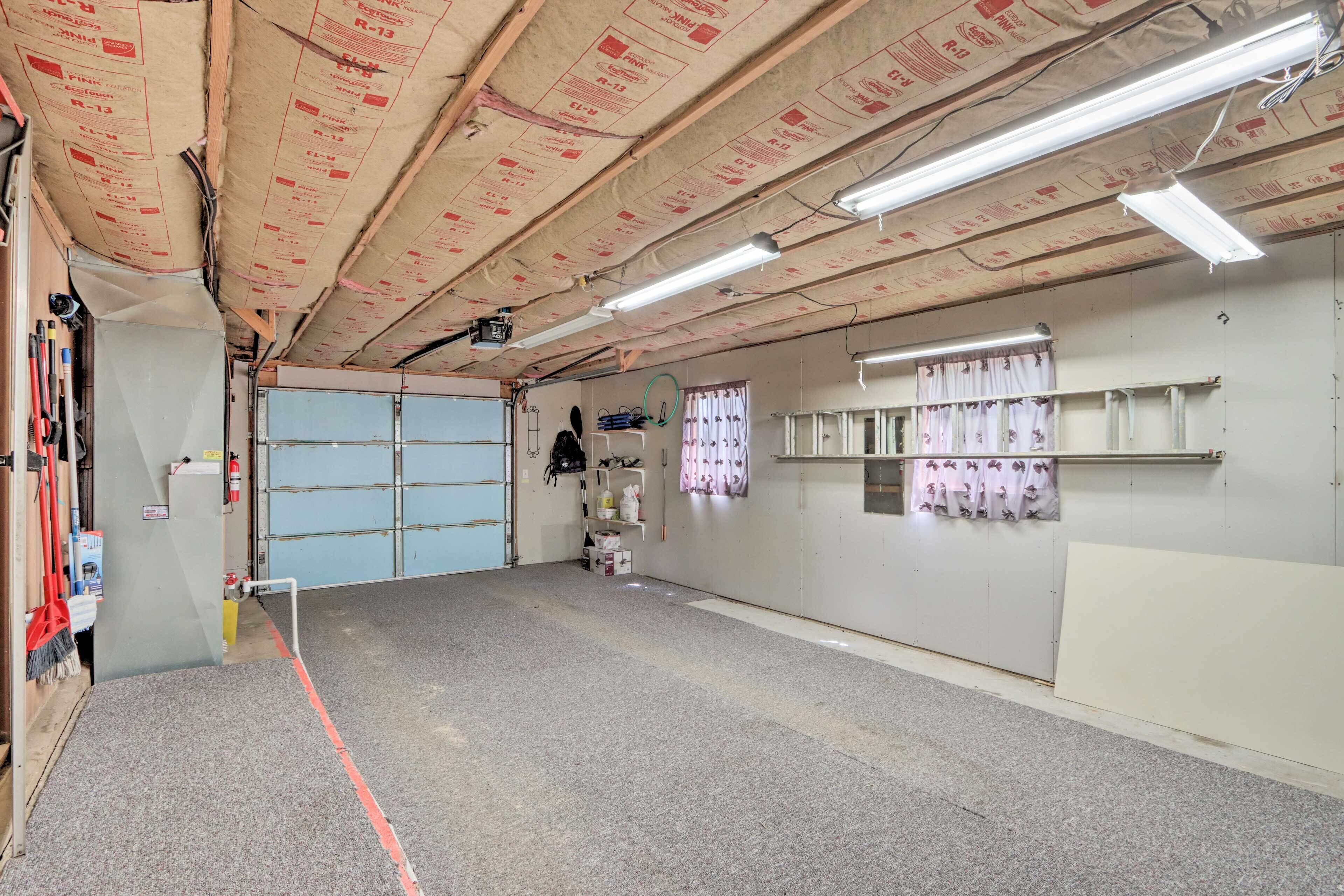 Ruime kamer met een hoge plafond, fluorescent verlichting, een blauwe deur en een witte muur met een plank waarop spullen staan.