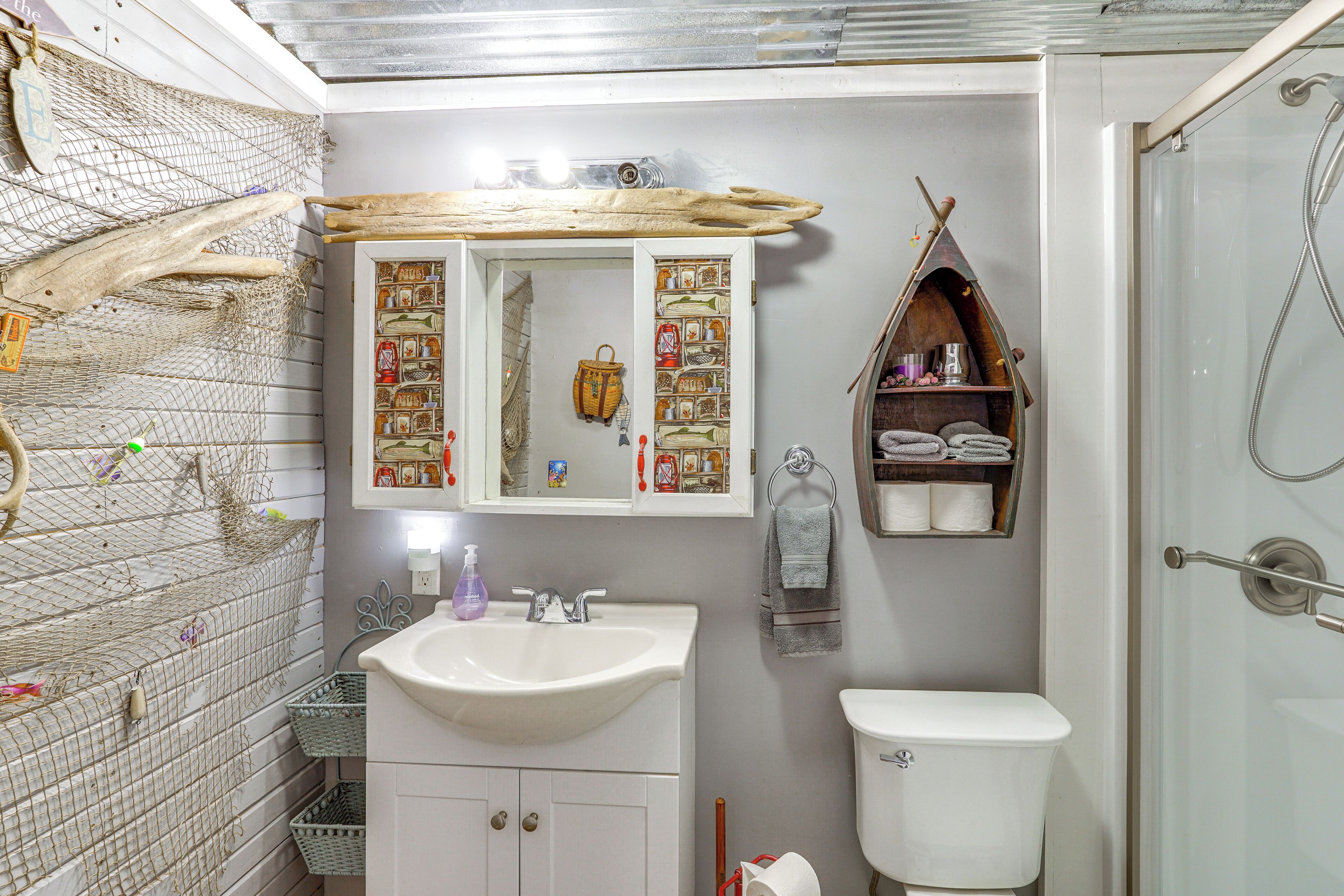 Un baño con un lavamanos blanco, un espejo con marco decorativo, un inodoro y una zona de ducha.