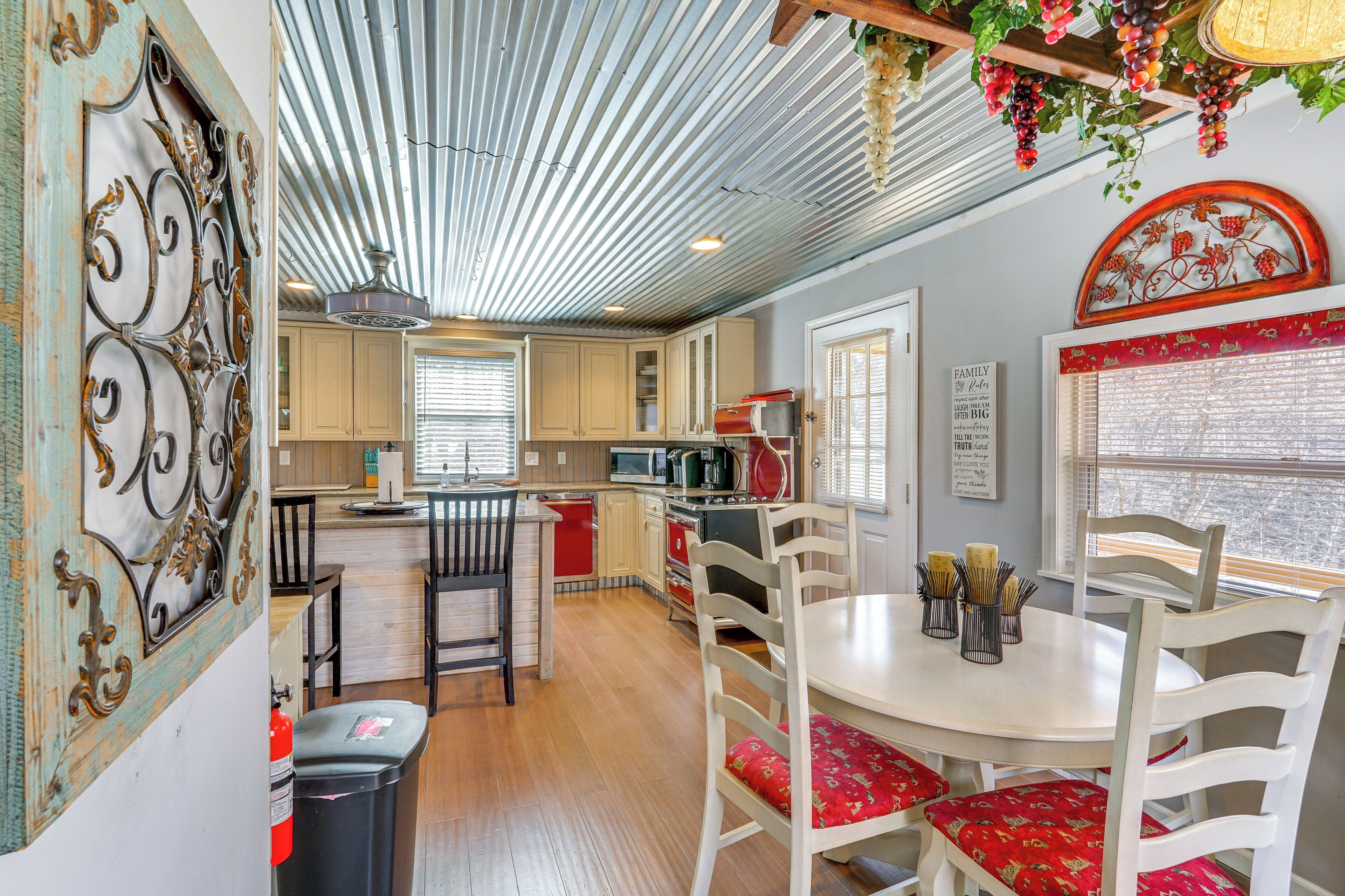 A kitchen with wooden cabinets, a red refrigerator, and a white dining table with red upholstered chairs.