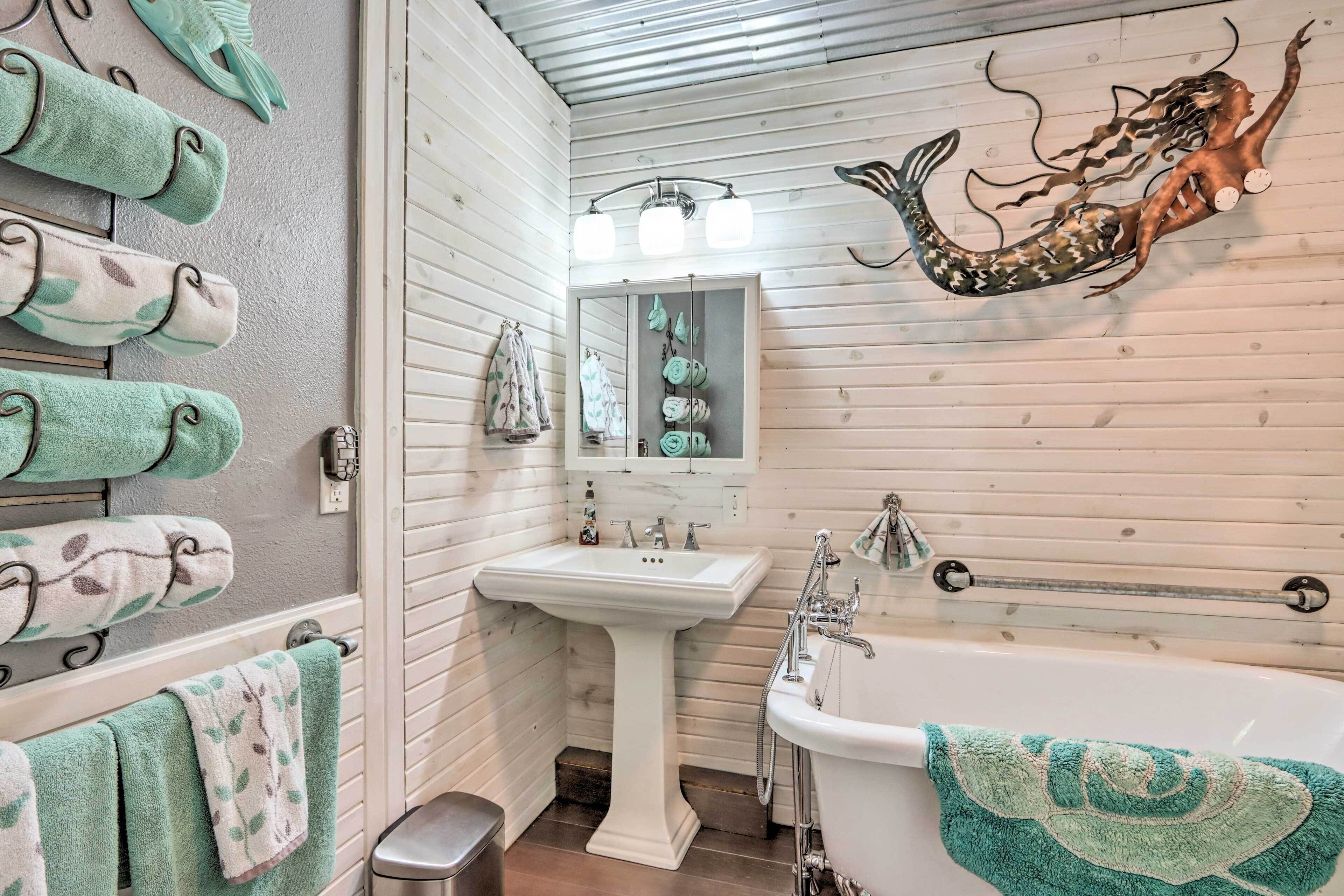 A bathroom with a sink, bathtub, and decorative wall art.