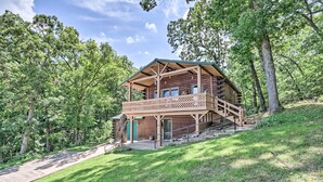 A wooden cabin with a balcony, surrounded by trees.