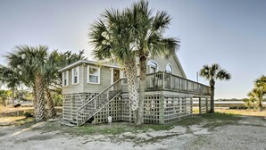 A two-story house with a wooden deck and a staircase leading to a balcony. - Cozy Waterfront 'island House' on Live Oak Island! (Crawfordville)