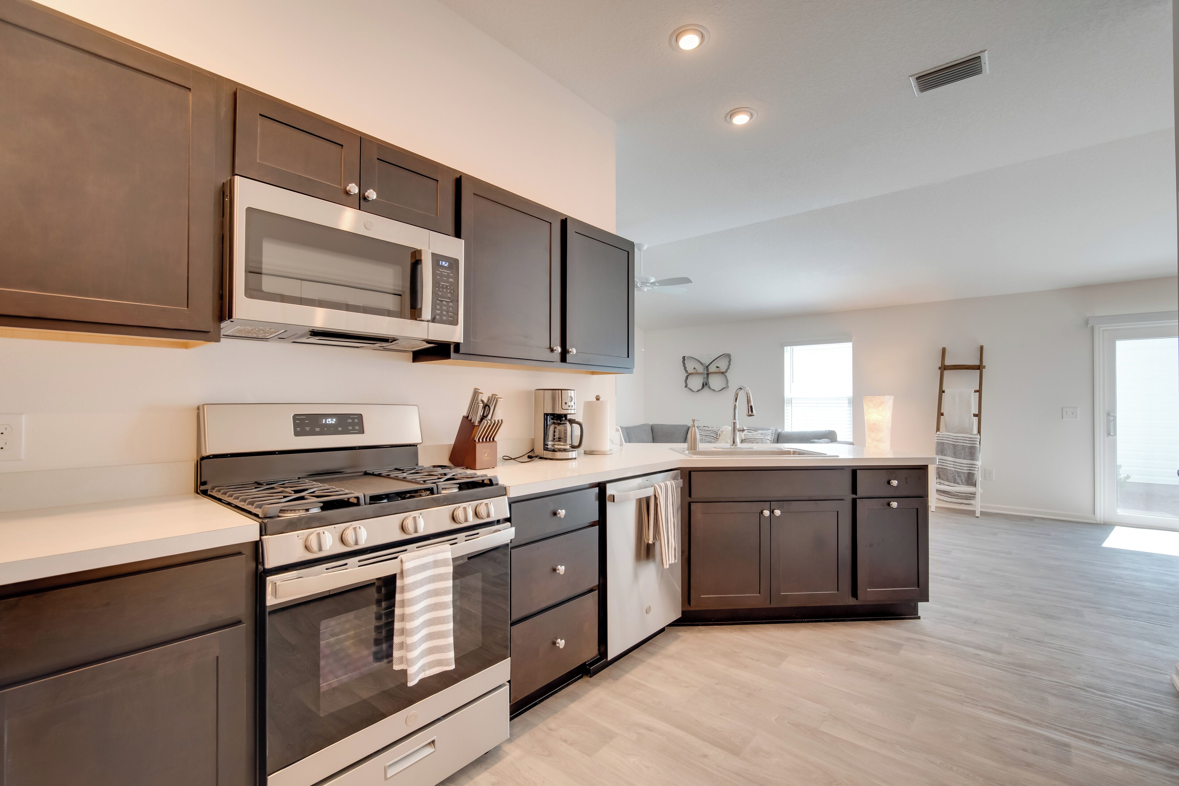 A modern kitchen with dark cabinets, stainless steel appliances, and a light-colored countertop.