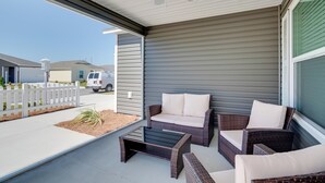 Eine überdachte Terrasse mit Korbmöbeln und Deckenventilator.