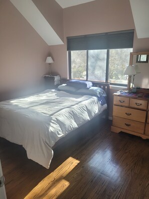 Relax in this serene bedroom with a large bed, sloped ceiling, and a dresser for ample storage.