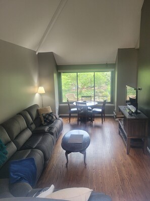 Relax in a serene atmosphere with a view of the lush garden from the large window. Enjoy comfortable seating on the sofa and ottoman, and dine or socialize at the small table with chairs.