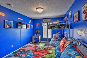Une chambre aux murs bleus, avec un lit superposé et des décorations sur le thème des super-héros.