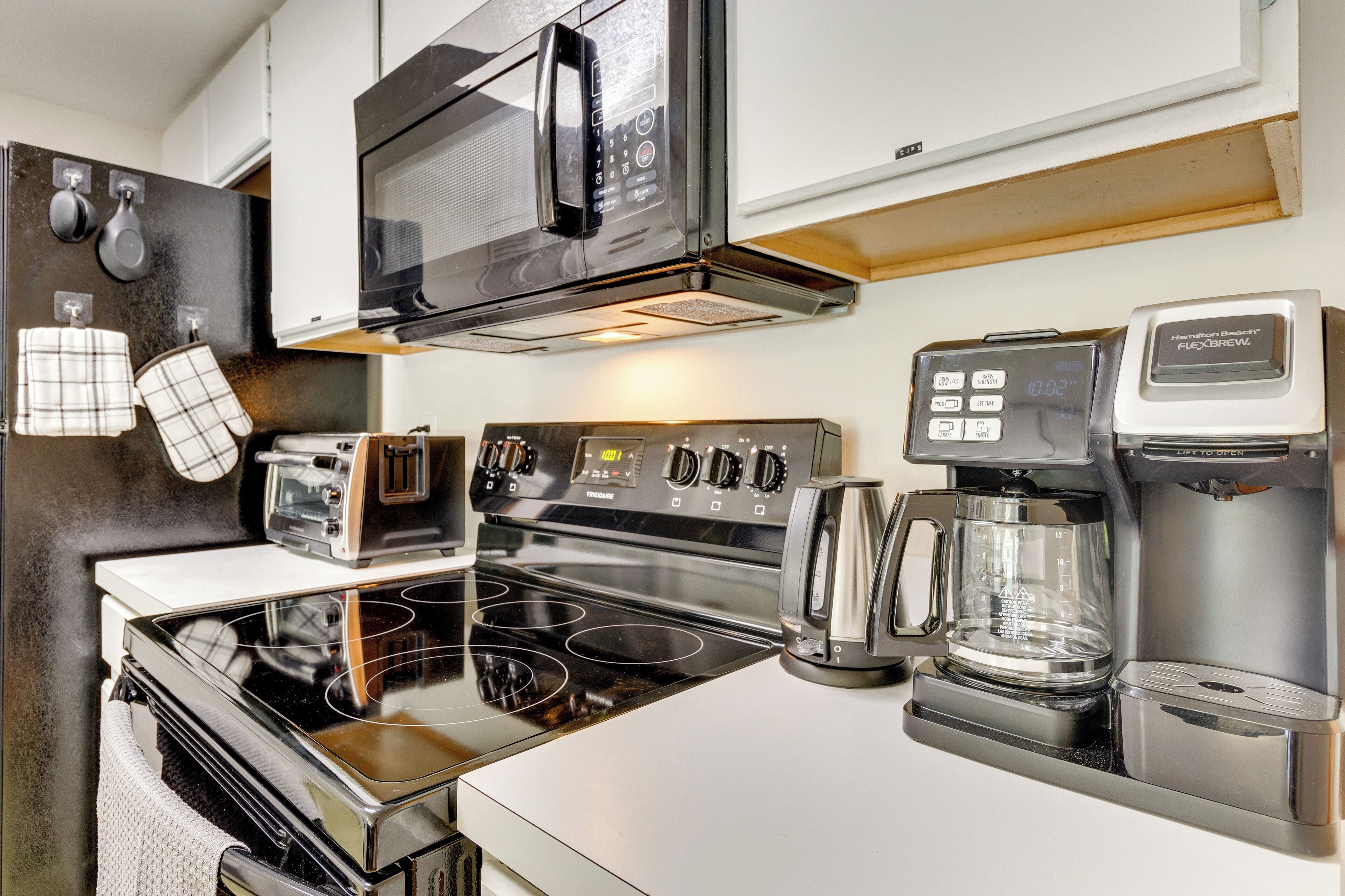 A modern kitchen with a stove, microwave, toaster, and coffee maker.