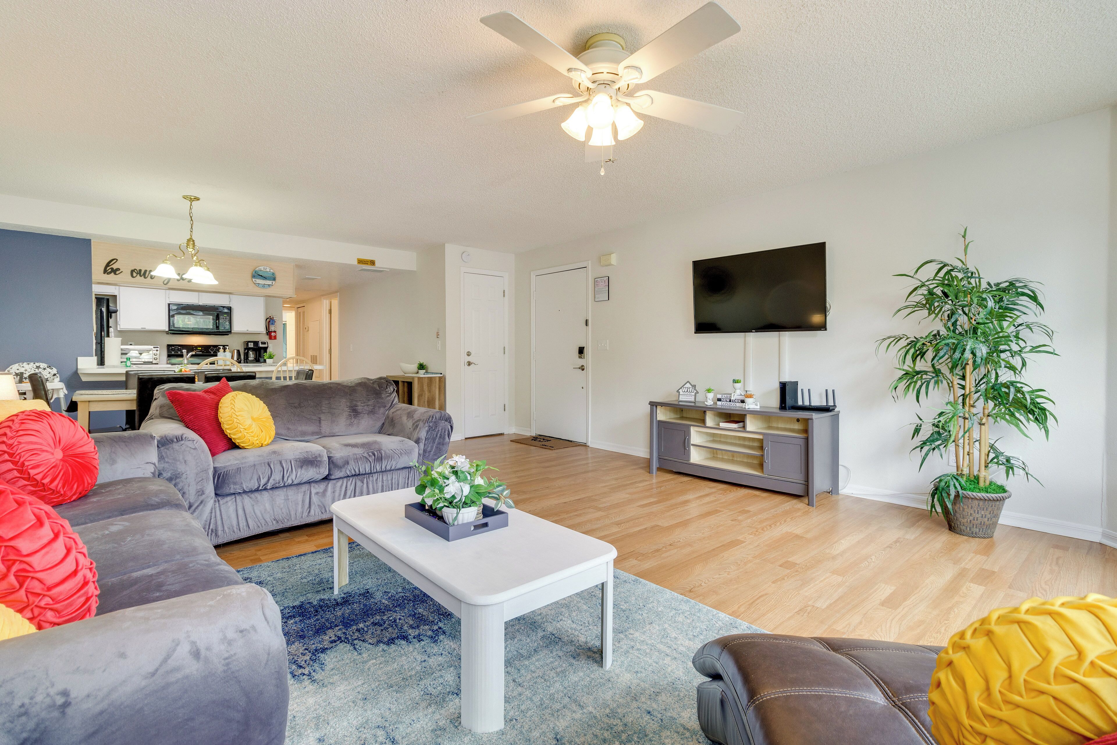 A modern living room with a grey sofa, a white coffee table, and a television mounted on the wall.