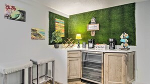 Une cuisine avec un mur vert, une machine à café et un panneau indiquant « bar à café ».