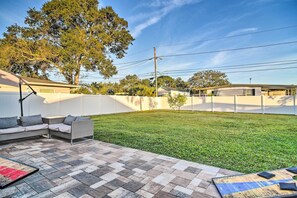 A backyard with a patio area, a lawn, and a white fence. - Sunny Seminole Home: Grill, Fire Pit & Fenced Yard (Seminole)