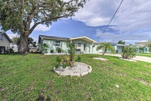 A two-story house with a large tree in the front yard, surrounded by a well-maintained lawn and small plants. - Canalfront Hudson Home W/private Dock & Yard! (Hudson)