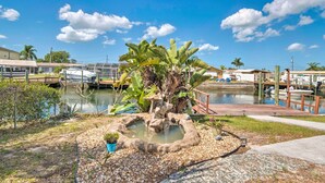 A serene outdoor area with a small pond, lush greenery, and a wooden dock extending into a calm water body. - Canalfront Hudson Home W/private Dock & Yard! (Hudson)