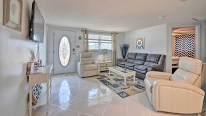 A living room with a sofa, armchair, coffee table, and a television mounted on the wall. - Canalfront Hudson Home W/private Dock & Yard! (Hudson)