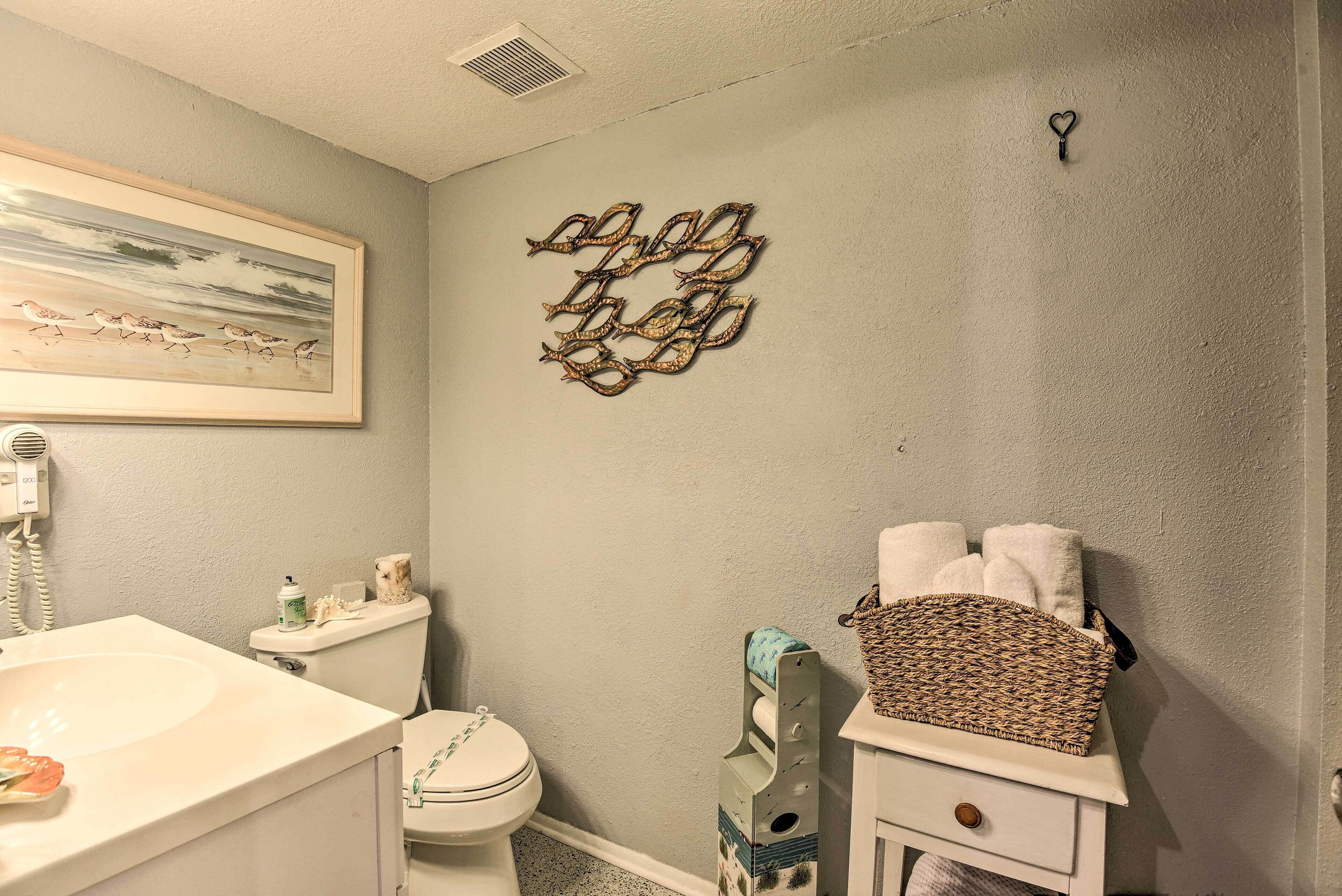 A bathroom with a toilet, sink, and decorative wall art.