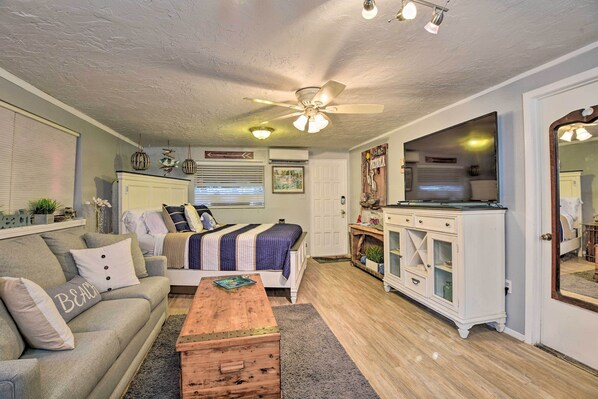 A cozy bedroom with a bed, bedside table, dresser, and a large mirror.