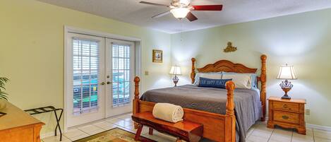 A bedroom with a bed, a bench, a ceiling fan, a nightstand, and a window with blinds.