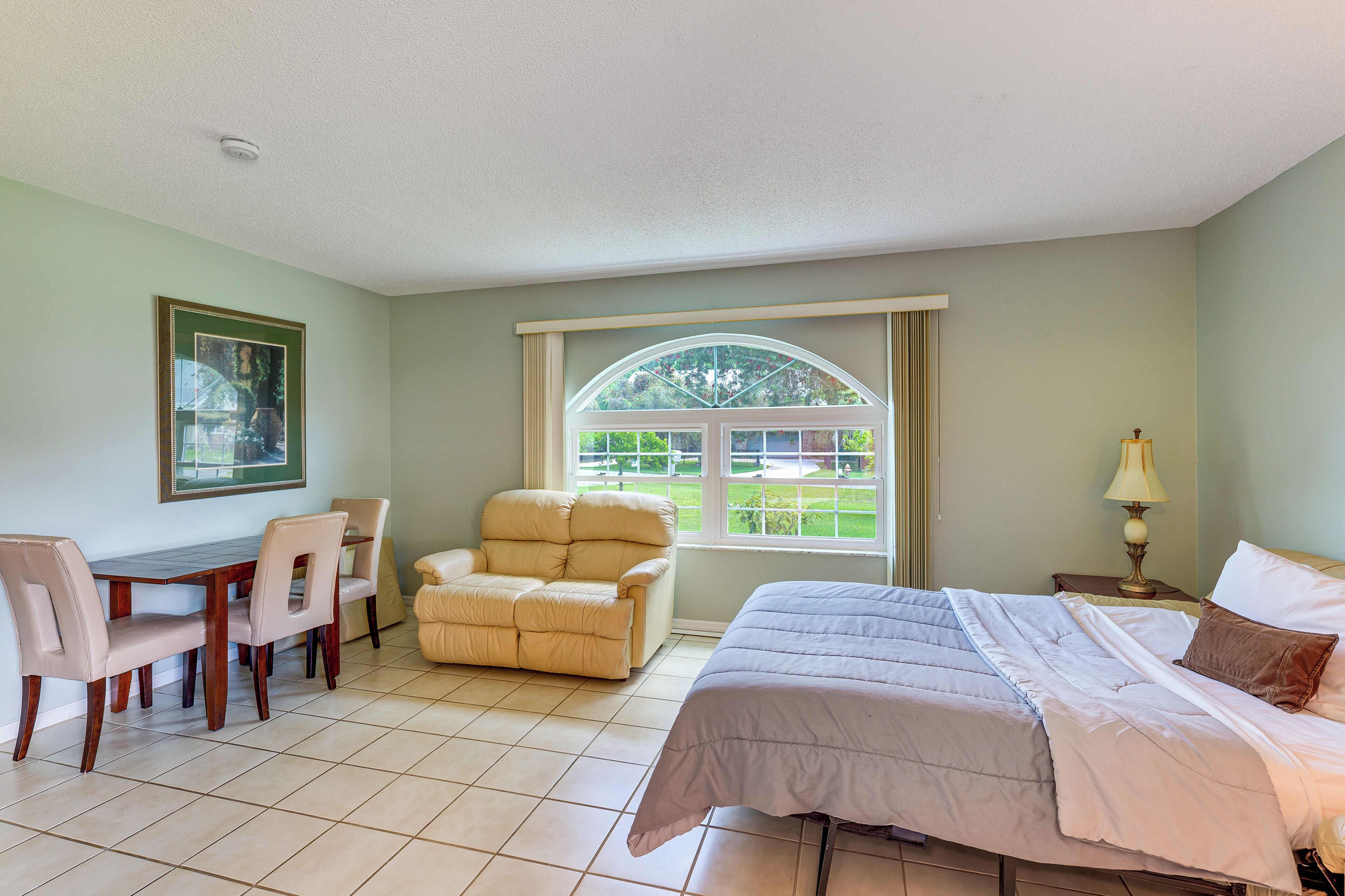 A room with a bed, a desk, a chair, and a window with a view.