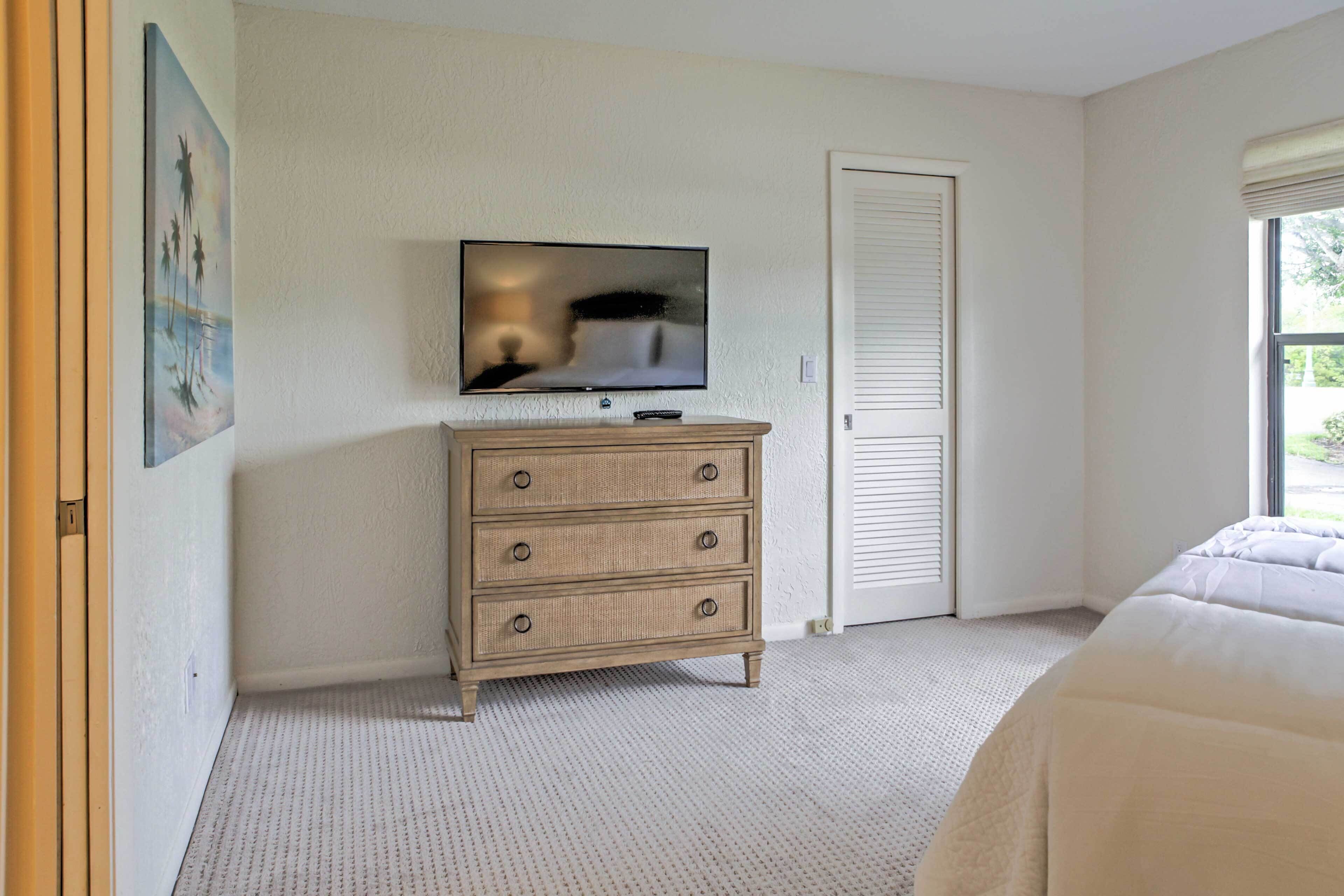 A bedroom with a bed, a wooden dresser, a television, and a door.