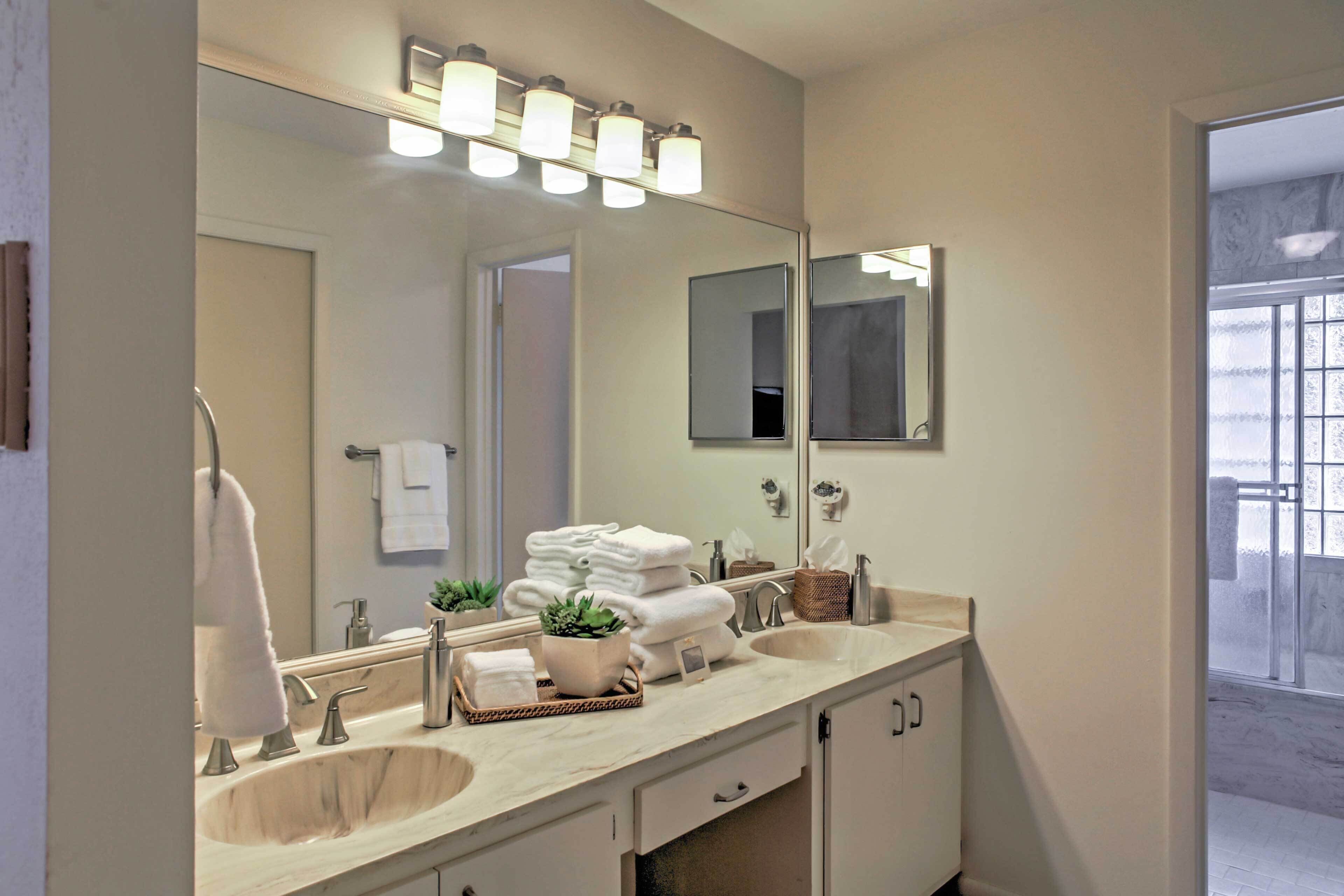 Une salle de bain dotée d’un grand miroir, de deux lavabos et d’un meuble-lavabo avec des placards.