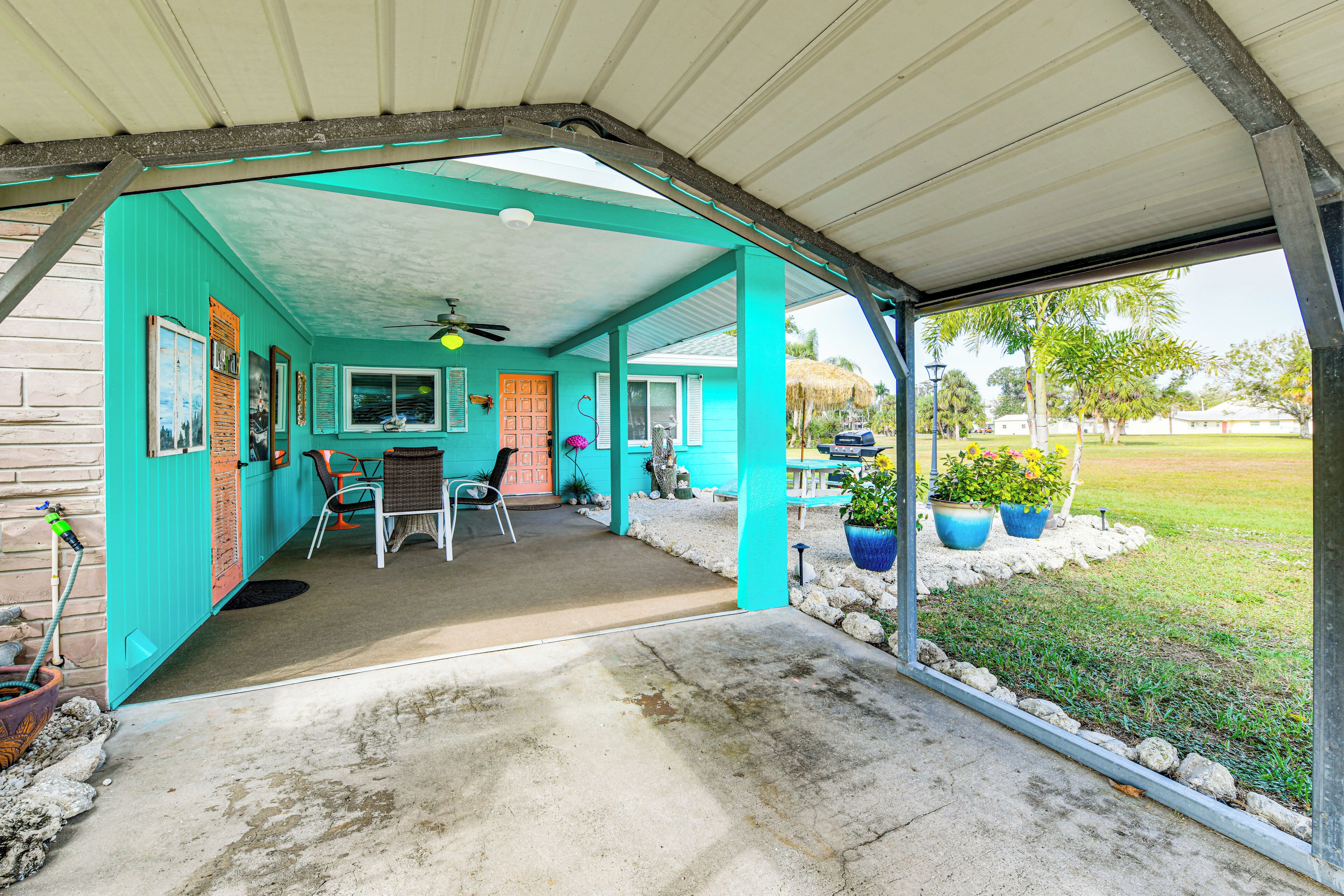 A covered patio area with a concrete floor, a ceiling fan, and a view of a grassy yard.