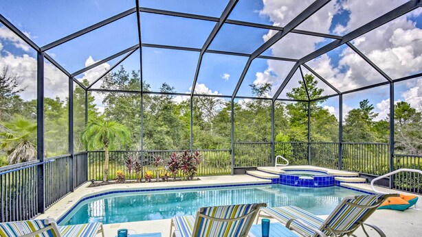 A covered outdoor swimming pool with lounge chairs and a hot tub.