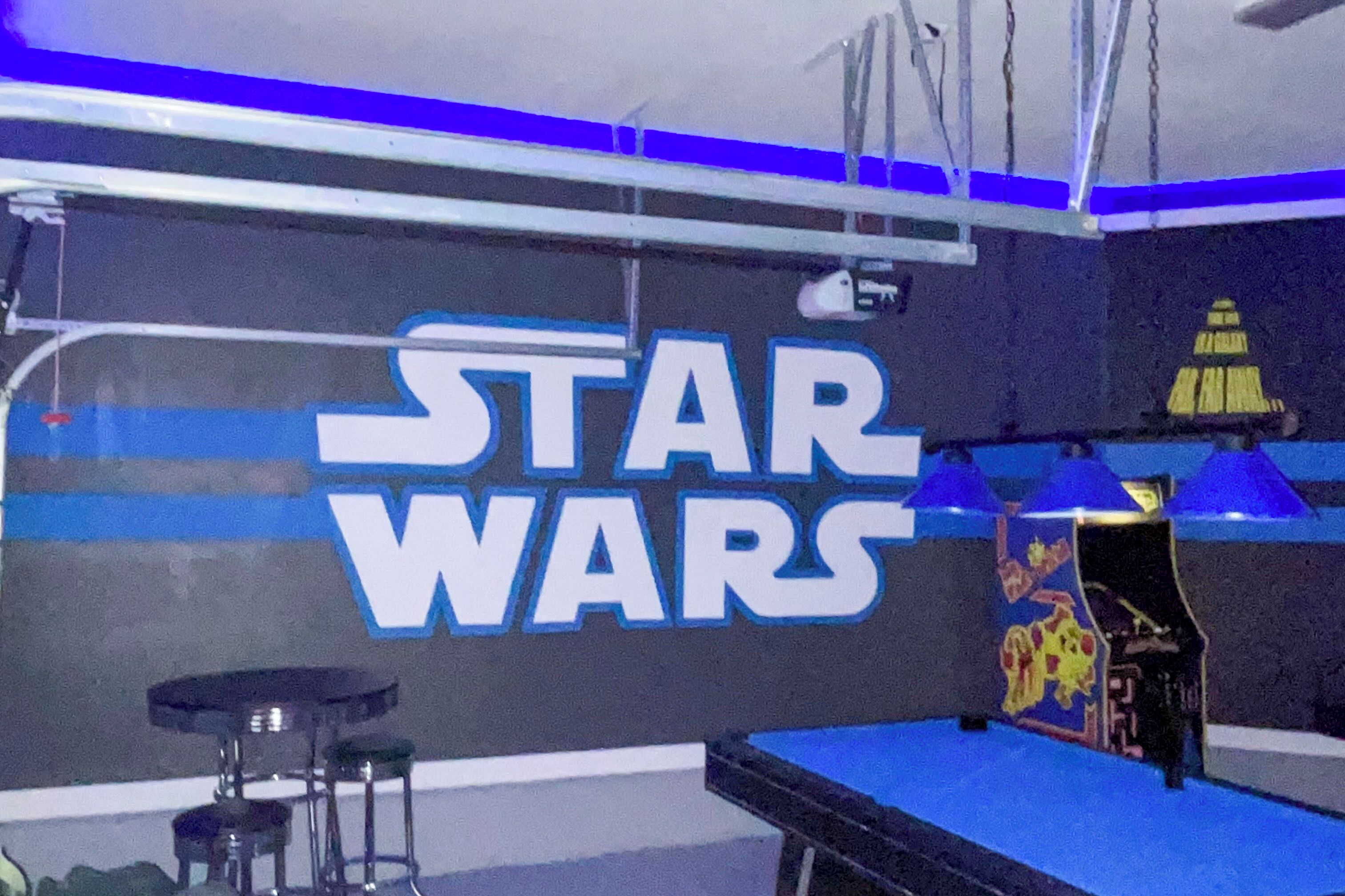 Ein Raum mit Wandgestaltung im Stil von Star Wars, einem Billardtisch und Barhocker.
