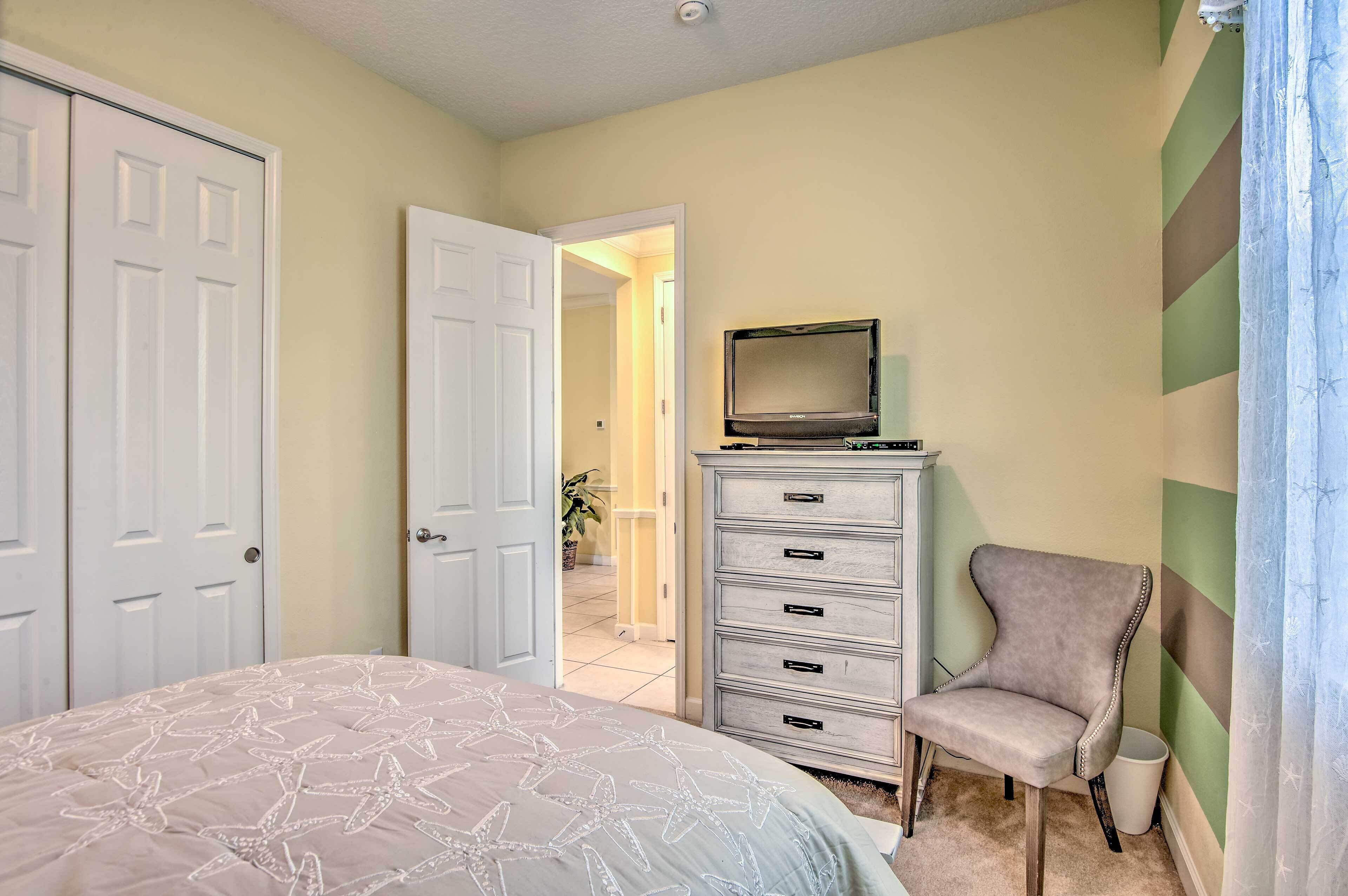 Une chambre à coucher avec un lit, une commode, une chaise et un téléviseur.