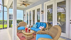 A covered porch with wicker furniture, a ceiling fan, and a view of the outdoors.