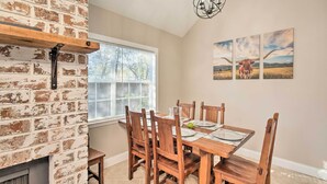 A dining area with a brick wall, wooden table, and chairs. - A-frame Retreat in Pensacola, 10 Mi to Dtwn (Pensacola)