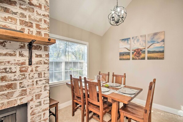 A dining area with a brick wall, wooden table, and chairs. - A-frame Retreat in Pensacola, 10 Mi to Dtwn (Pensacola)