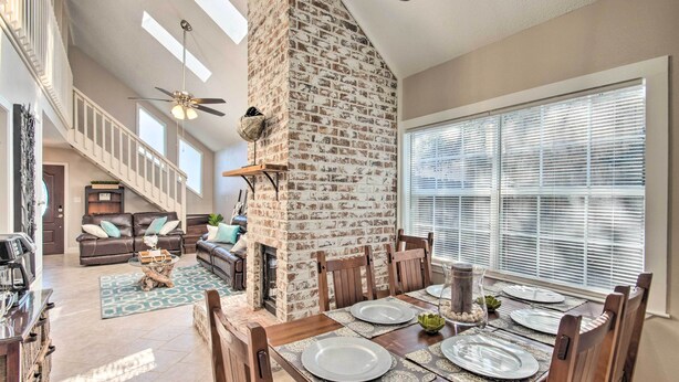 A spacious living area with a high ceiling, a fireplace, and a dining table set for four. - A-frame Retreat in Pensacola, 10 Mi to Dtwn (Pensacola)