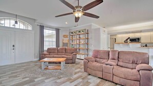 A spacious living room with a ceiling fan, two sofas, a coffee table, and a built-in bookshelf.