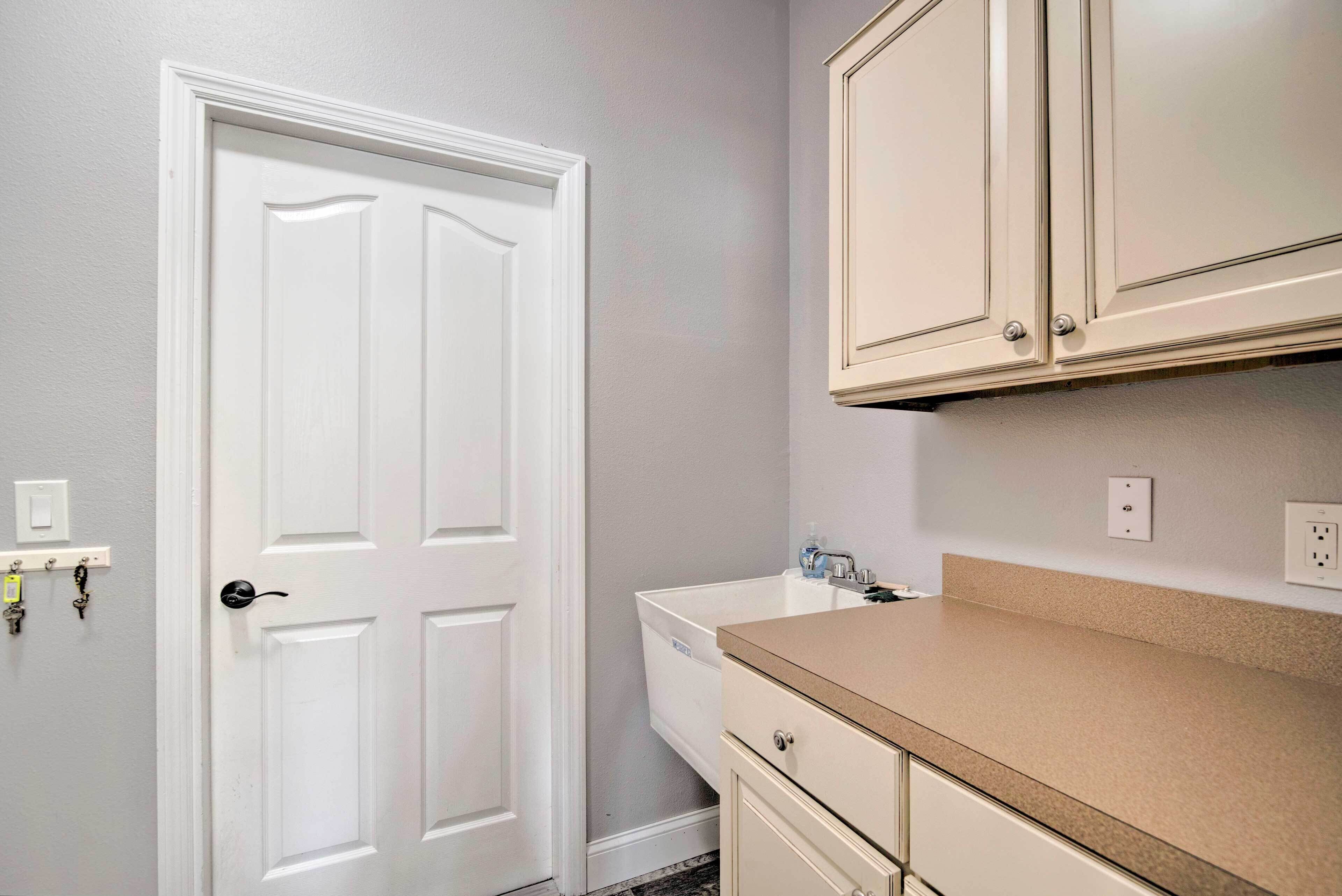 A bathroom with a white door, a sink, and cabinets.