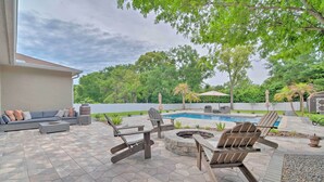 An outdoor patio with a pool, seating area, and fire pit.