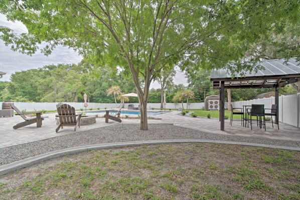 A backyard with a pool, outdoor furniture, and a pergola.