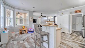A spacious kitchen with a central island, wooden flooring, and a dining area with a table and chairs.