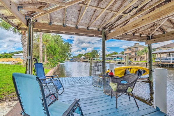 Relax on the deck overlooking the serene water, surrounded by lush greenery and a picturesque view.