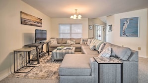 A living room with a sectional sofa, a flat-screen TV, a coffee table, and a chandelier. - Waterfront Home w/ Dock, Kayaks, Pool + More! (Crystal River)