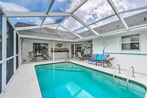 Relax by the pool surrounded by lounge chairs and a kitchen area.